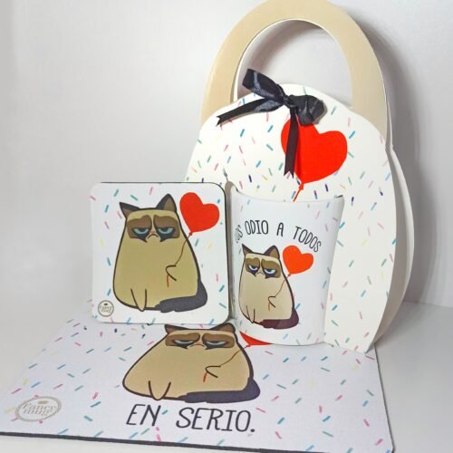 Kit que incluye taza, porta taza, posa taza y pad con ilustración de gatito estilo caricatura, corazones rojos y frases “Los odio a todos” y “En serio”, diseño divertido y sarcástico.